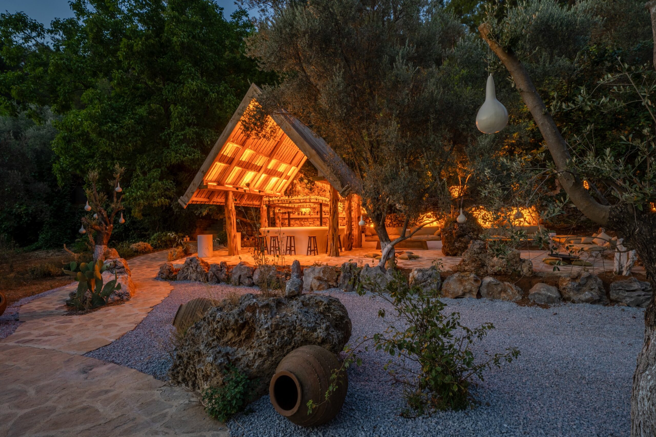 The open-air bar and lounge, lit at dusk among the olive trees