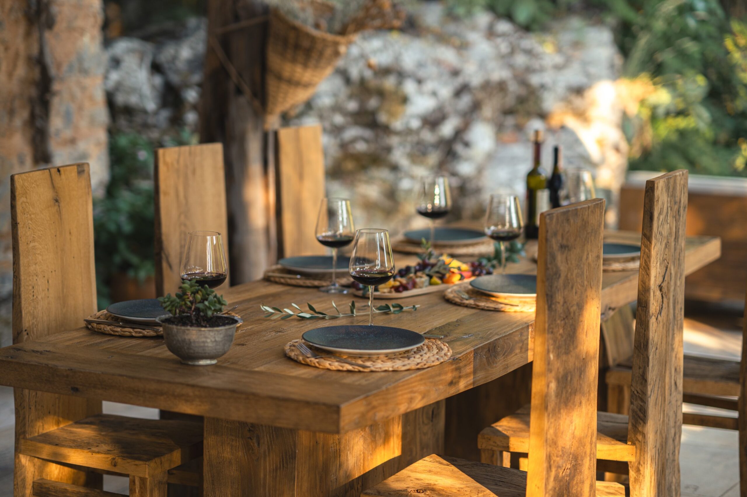 A long wooden table set for dinner, with wine poured and food laid out