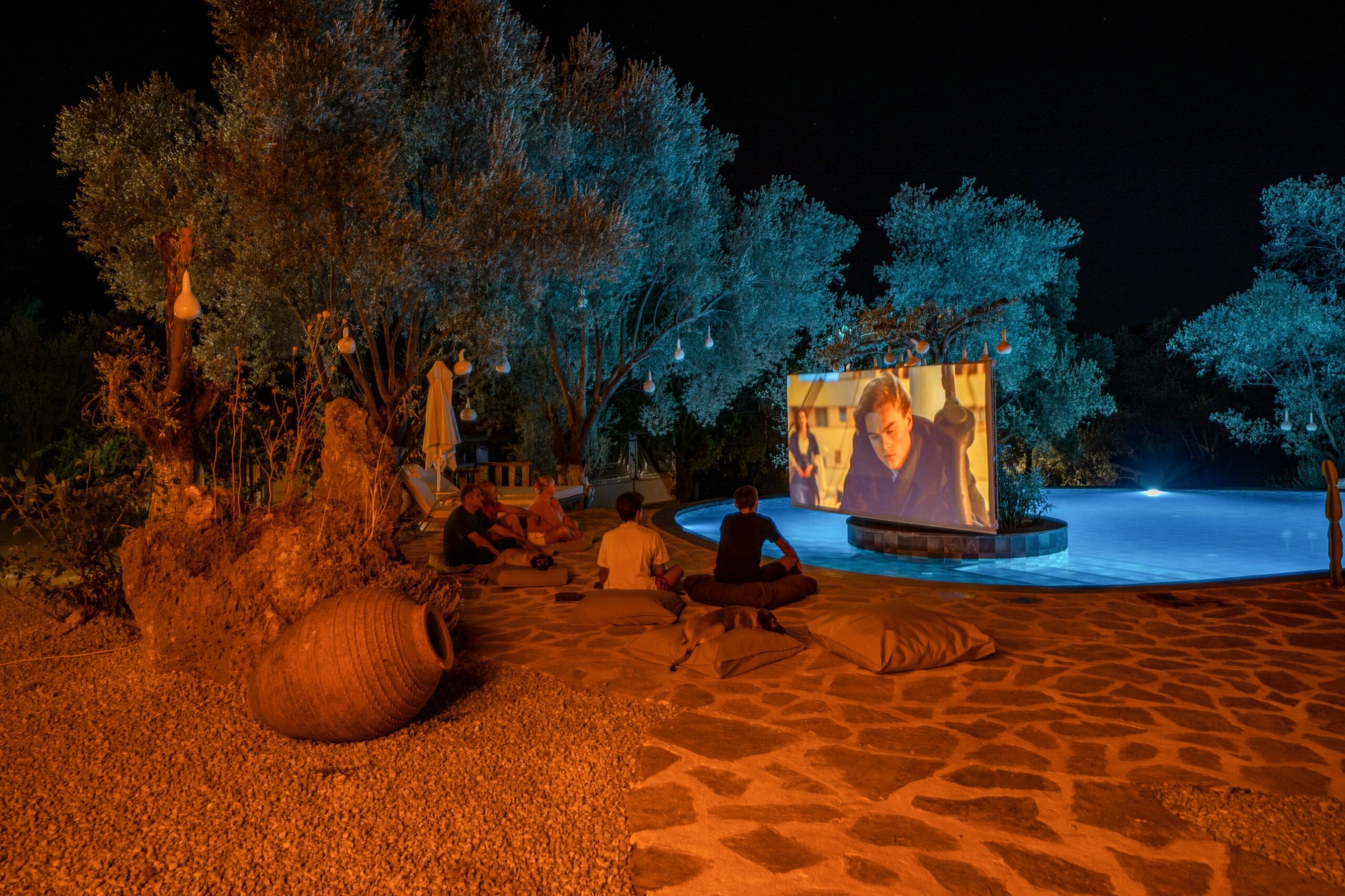 Outdoor film night by the pool, lanterns in the olive trees