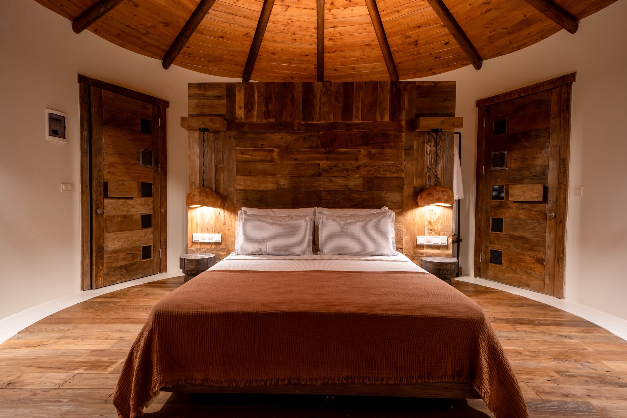 Round Deluxe bedroom with wood dome ceiling and terracotta bedspread
